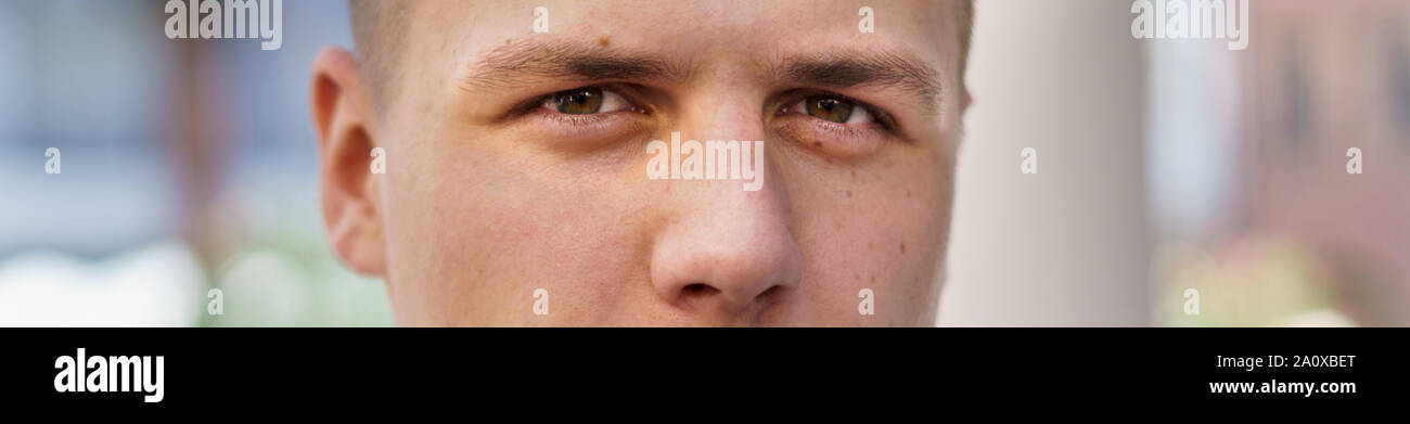 Dans une bannière Panorama close up portrait des yeux d'un jeune homme regardant attentivement à l'appareil photo à l'extérieur avec copie espace Banque D'Images