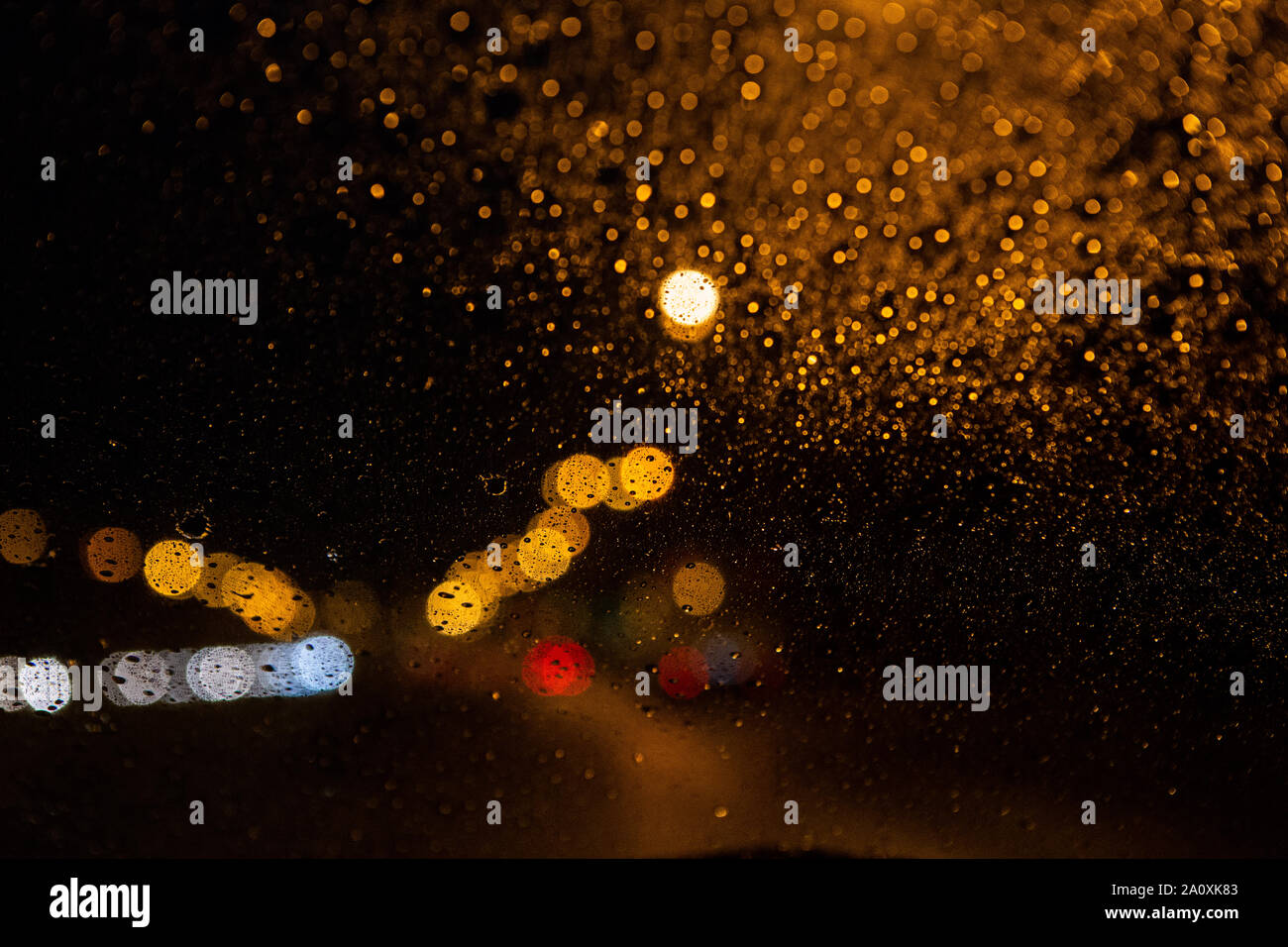 Arrière-plan flou. L'éclairage de rue à travers le pare-brise avec gouttes de pluie Banque D'Images