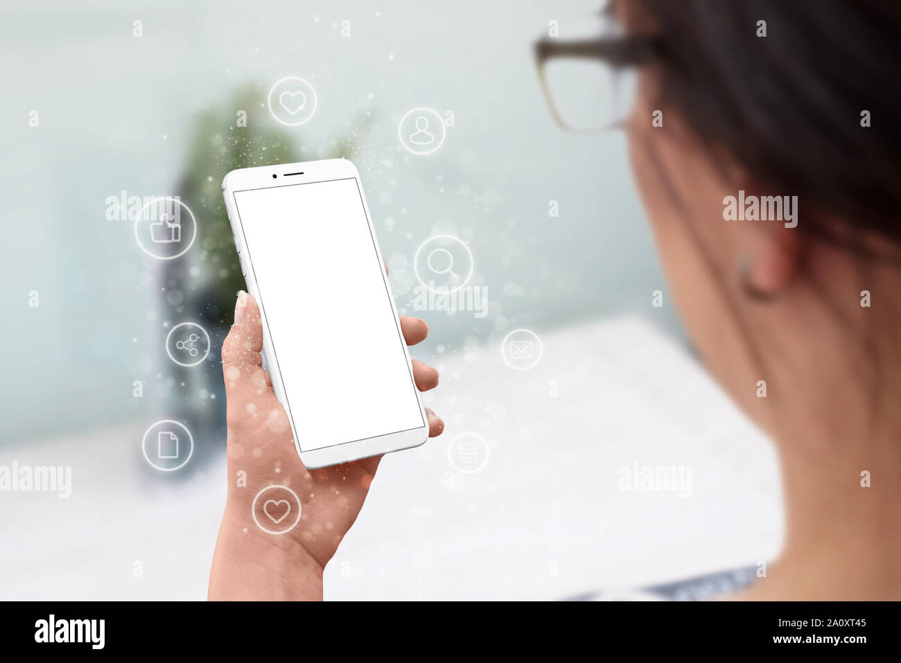 Woman hold smart phone moderne avec écran isolé pour une maquette. Internet des objets et icônes réseau concept entourent le téléphone. Banque D'Images