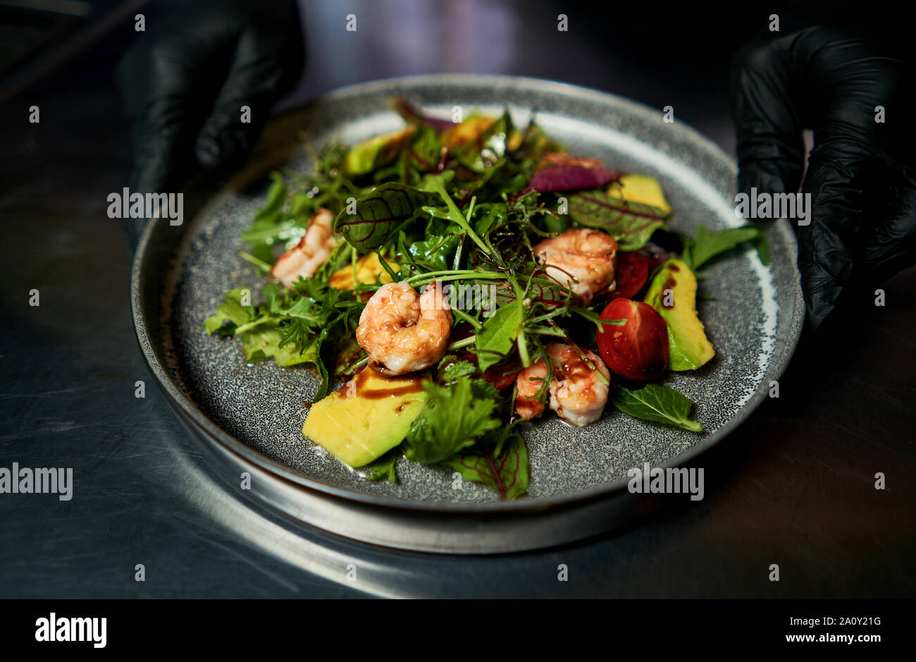 L'homme est titulaire d'une plaque avec une salade de crevettes et d'herbes Banque D'Images