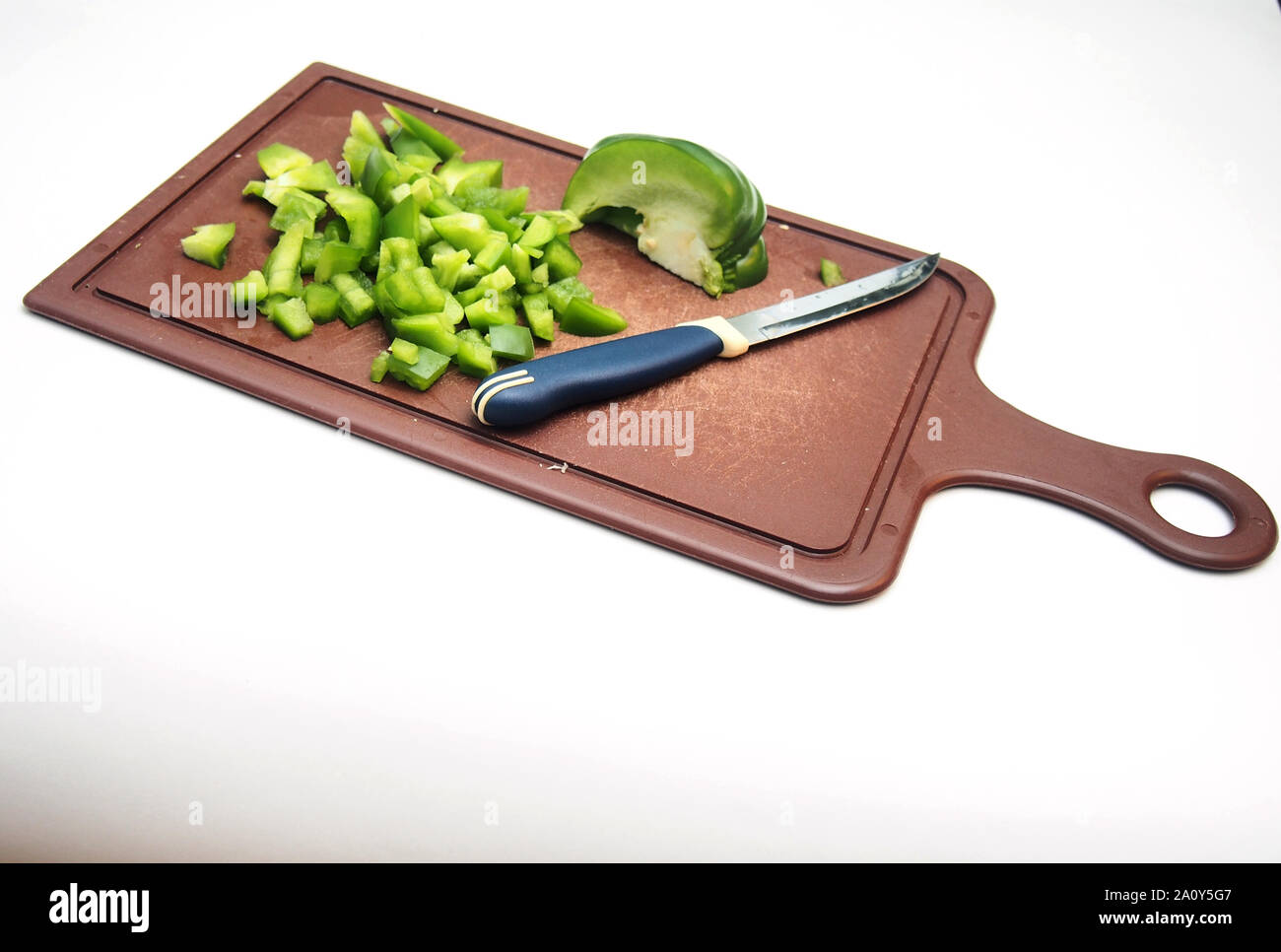 Fruits poivre vert se trouve sur la planche à découper. À côté du poivron est un couteau. La cuisson. Tranches de poivron. L'alimentation. Banque D'Images