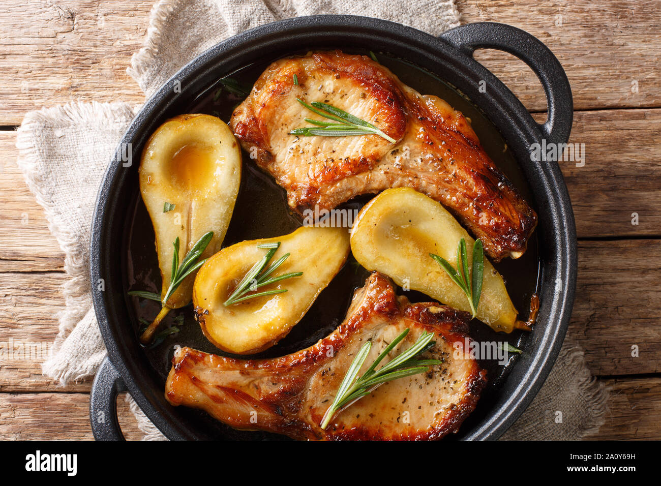 Maison de vacances recette de côtelettes de porc au four avec les poires et romarin en sauce au miel servi dans une casserole sur la table. Haut horizontale Vue de dessus Banque D'Images