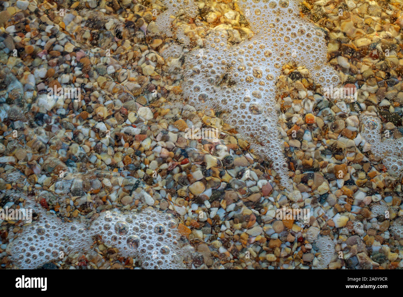 Galets de mer de granit de couleur sur le fond de plage de pierres. La rive de la plage de sable et cailloux lavés par les vagues de la mer. Banque D'Images