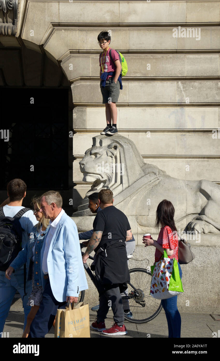 Garçon debout sur la tête de lion en pierre, à Nottingham Banque D'Images