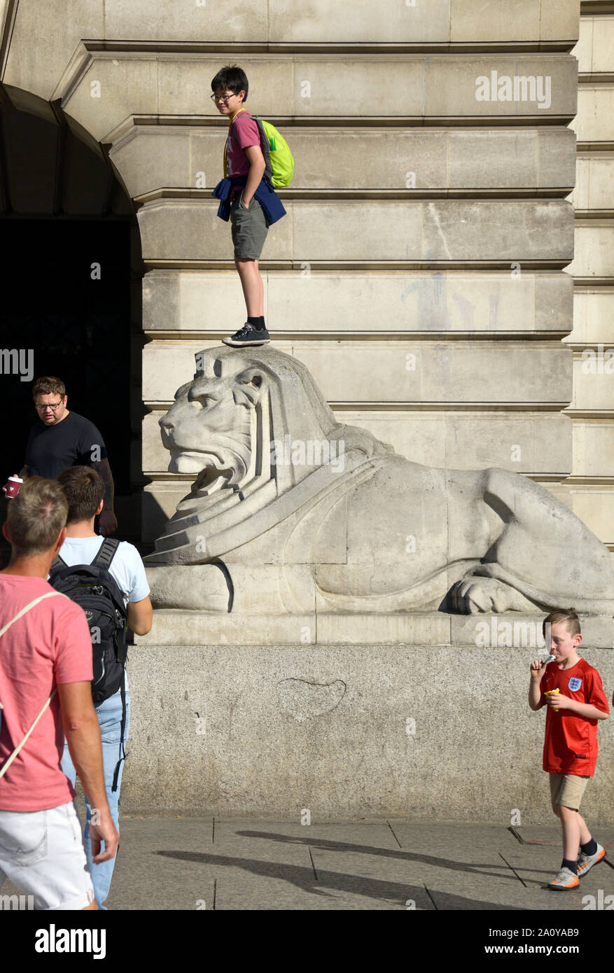 Garçon debout sur la tête de lion en pierre, à Nottingham Banque D'Images