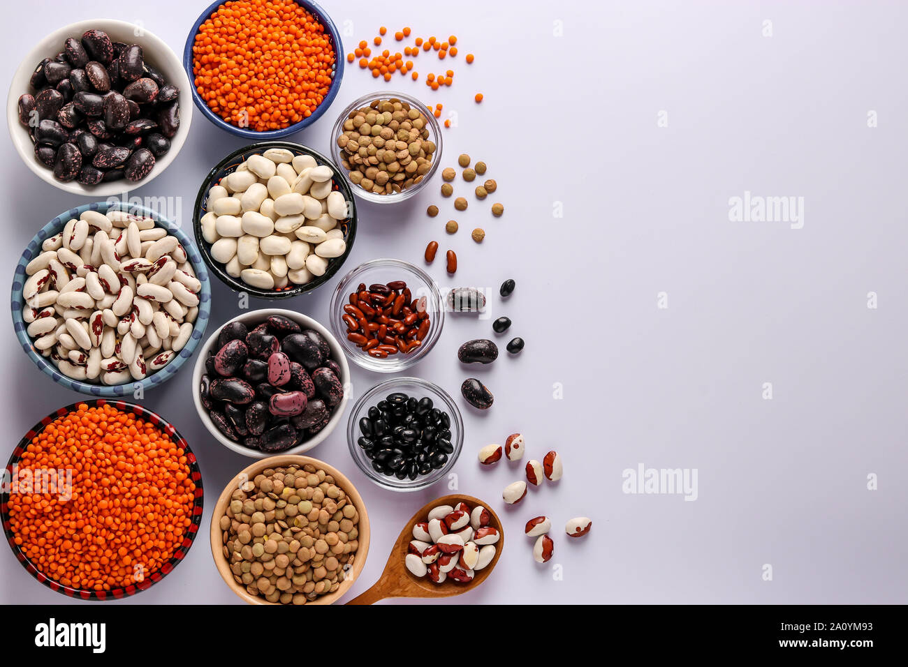 Lentilles rouge et brun, noir, marron et blanc, les haricots sont les légumes qui contiennent beaucoup de protéines sont situées dans des bols sur fond blanc, concept est Banque D'Images