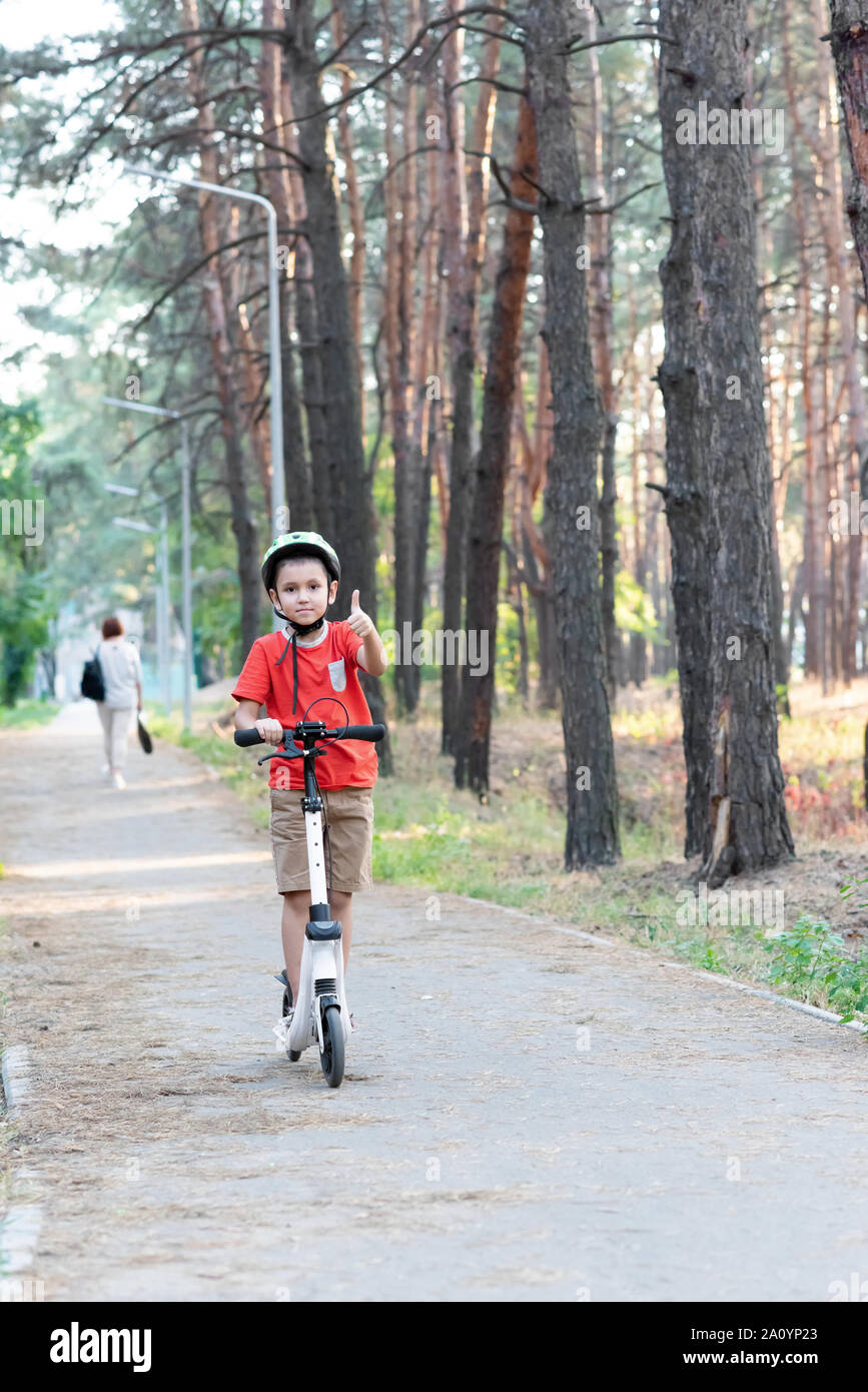 Un garçon fait un scooter dans la forêt. Banque D'Images