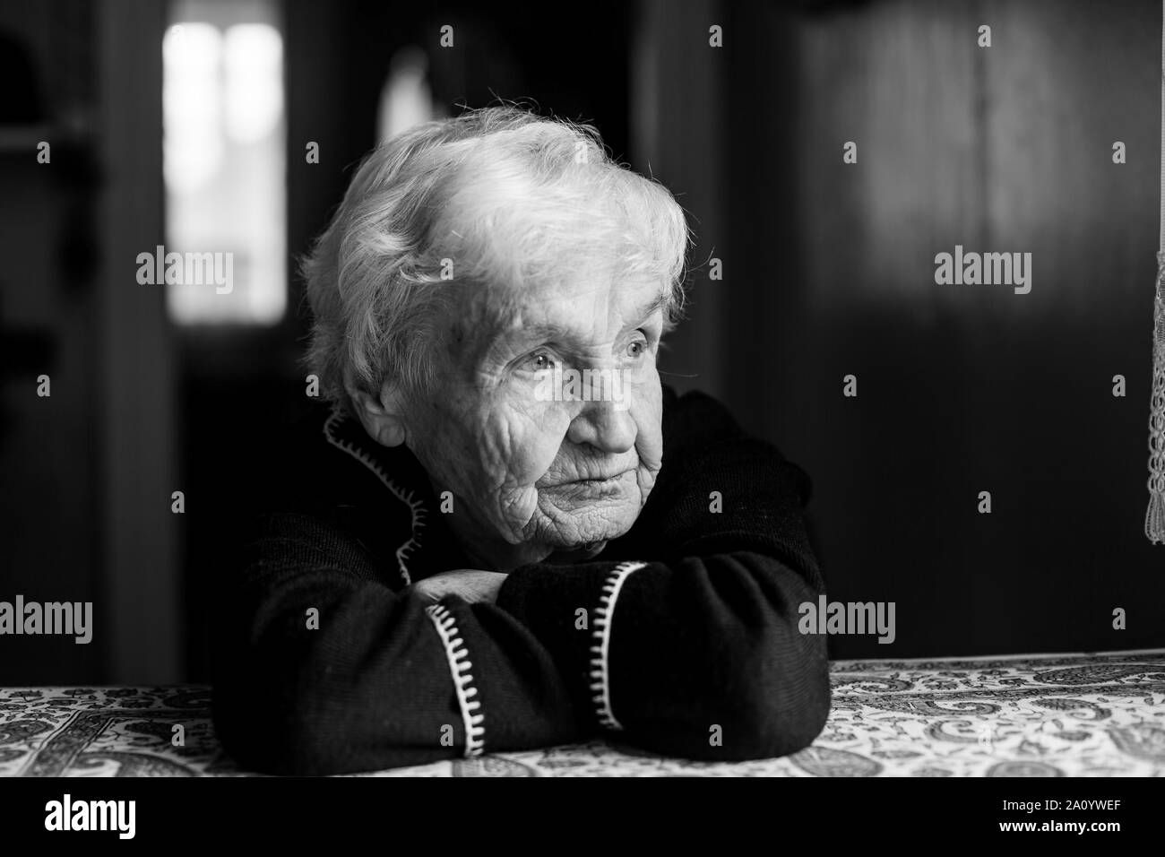 Portrait de vieille femme solitaire est assis à la table. Photo en noir et blanc. Banque D'Images