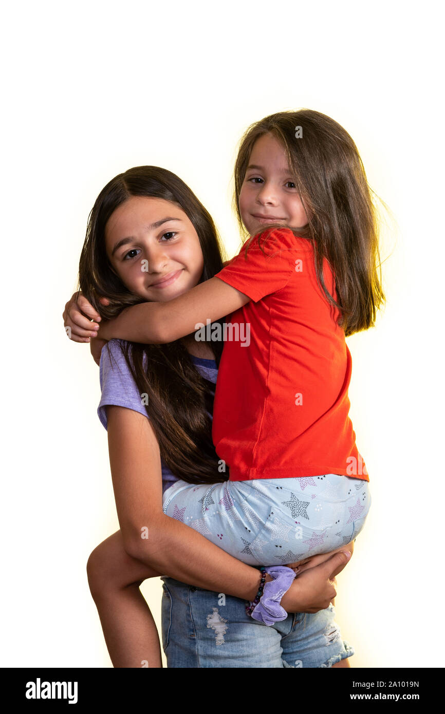 Young teen girl tenant dans ses bras son petit ami et heureusement regardant la caméra, isolé sur un fond blanc. Banque D'Images