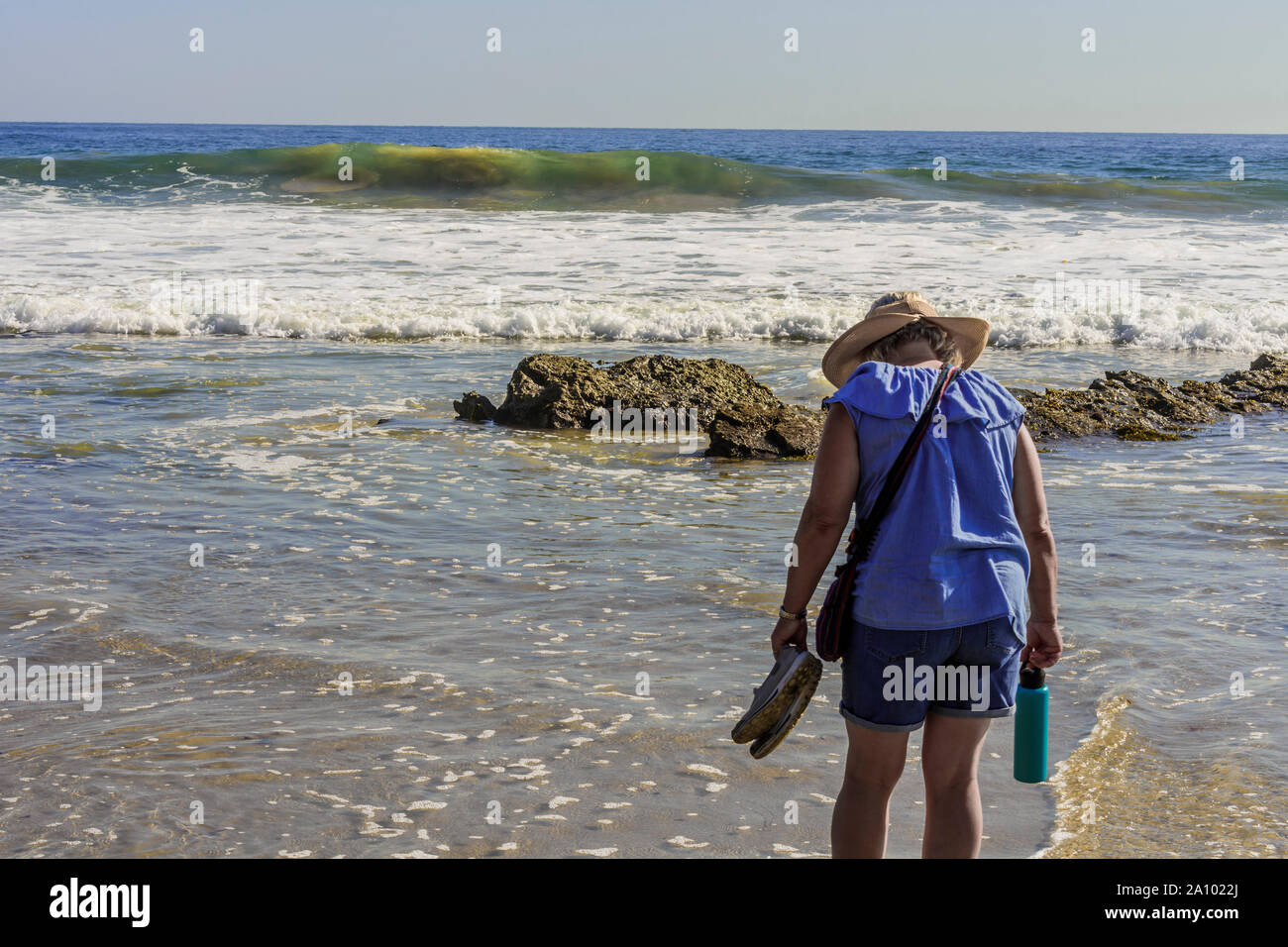 Femme marche sur le surf à la recherche de coquillages. Banque D'Images