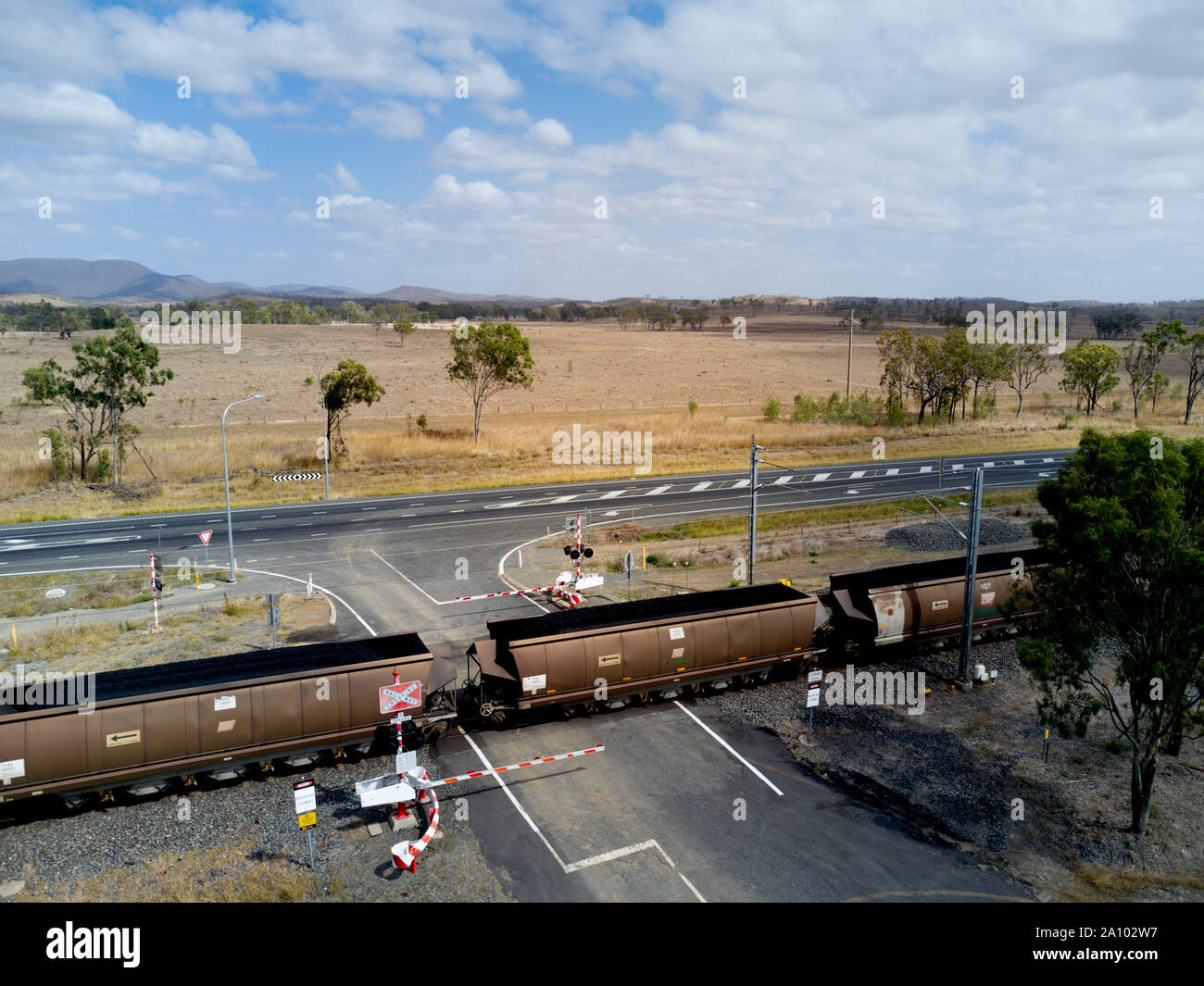 Train de charbon de grande hauteur avec 106 wagons en passant par un passage à niveau contrôlé de la flèche la position le long du côté de l'autoroute Bruce exportation Gladstone termina Banque D'Images