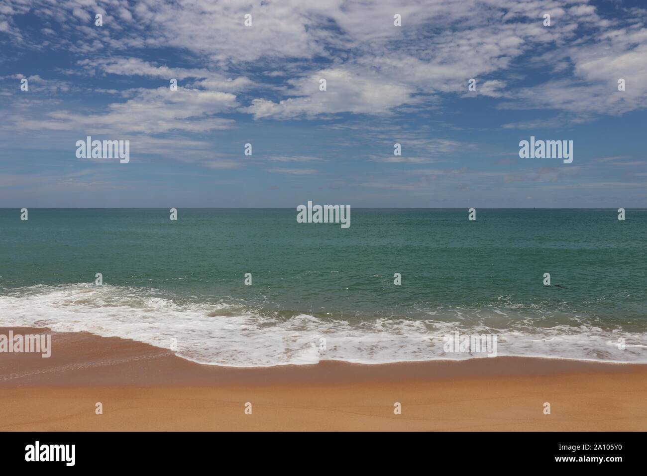 Seascape pittoresque avec de l'eau azur, ciel bleu et nuages blancs. Vue de la formation de mousse océan vagues léchant le sable Banque D'Images