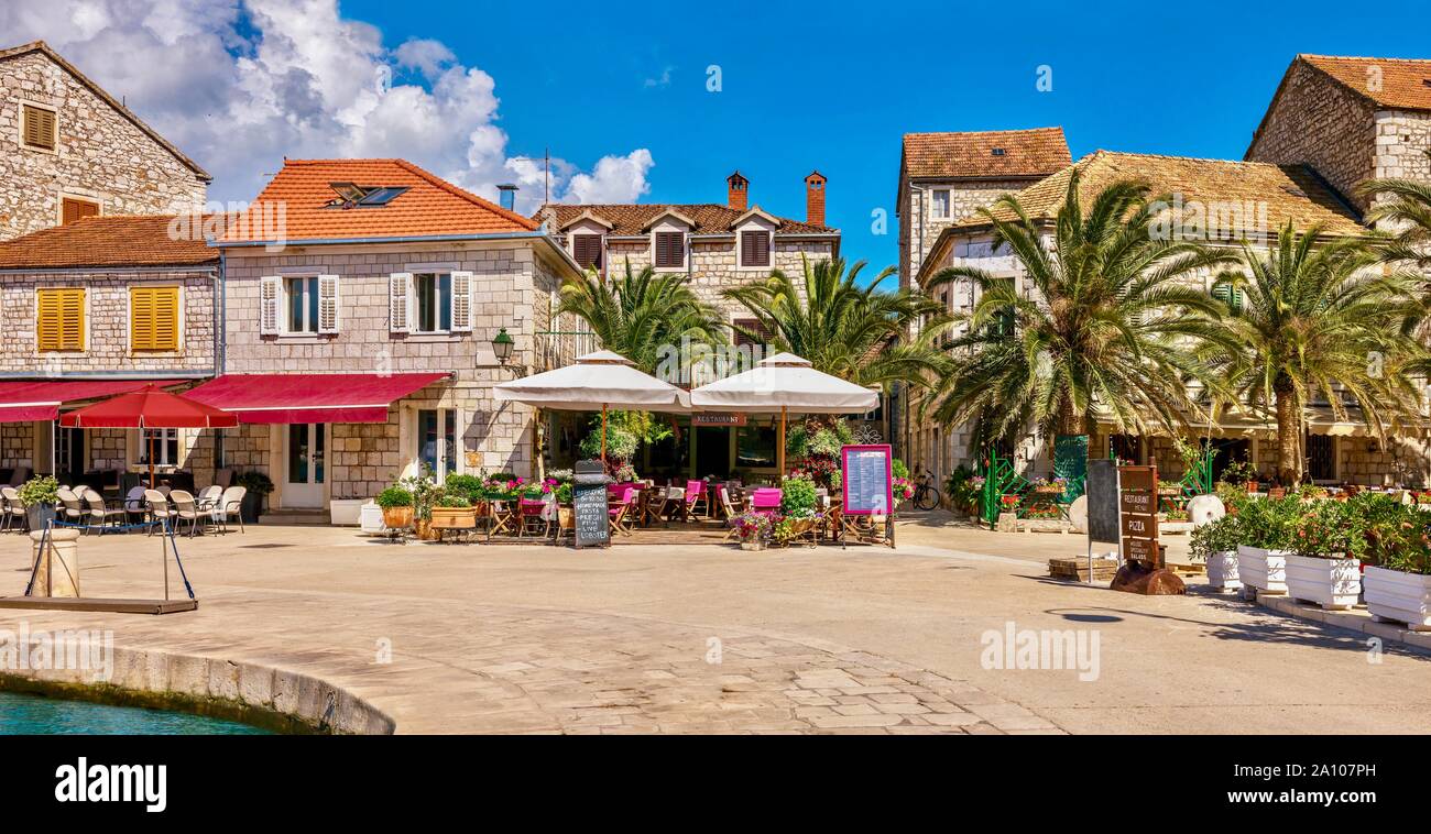 Un panorama coloré d'un complexe méditerranéen en été, avec restaurants et cafés le long de la promenade du bord de mer. Stari Grad, île de Hvar, Croatie. Banque D'Images