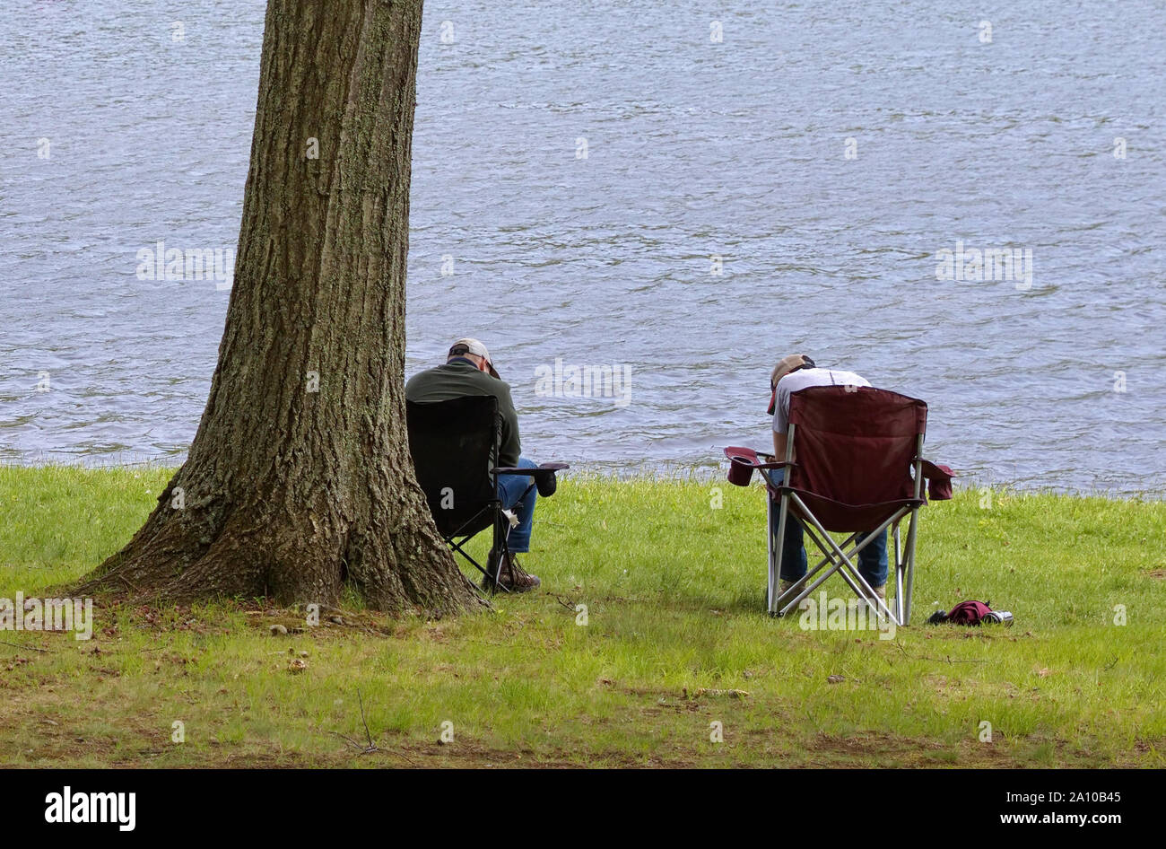 Père et fils par river shore assis sur des chaises de camping d'avoir une discussion sérieuse, ou une session de surf Banque D'Images