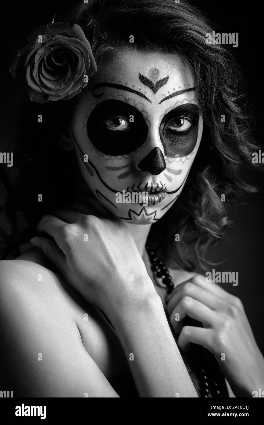 Jeune femme avec santa muerte maquillage sur fond noir looking at camera, monochrome Banque D'Images