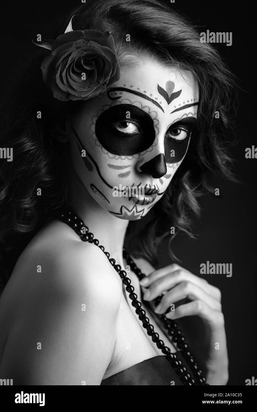 Jeune femme avec santa muerte maquillage sur fond noir looking at camera, monochrome Banque D'Images