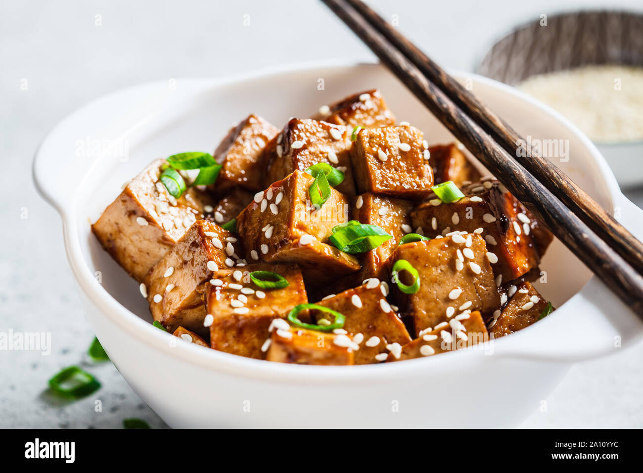 Tofu frit à la sauce teriyaki dans un bol blanc. La nourriture végane concept. Banque D'Images