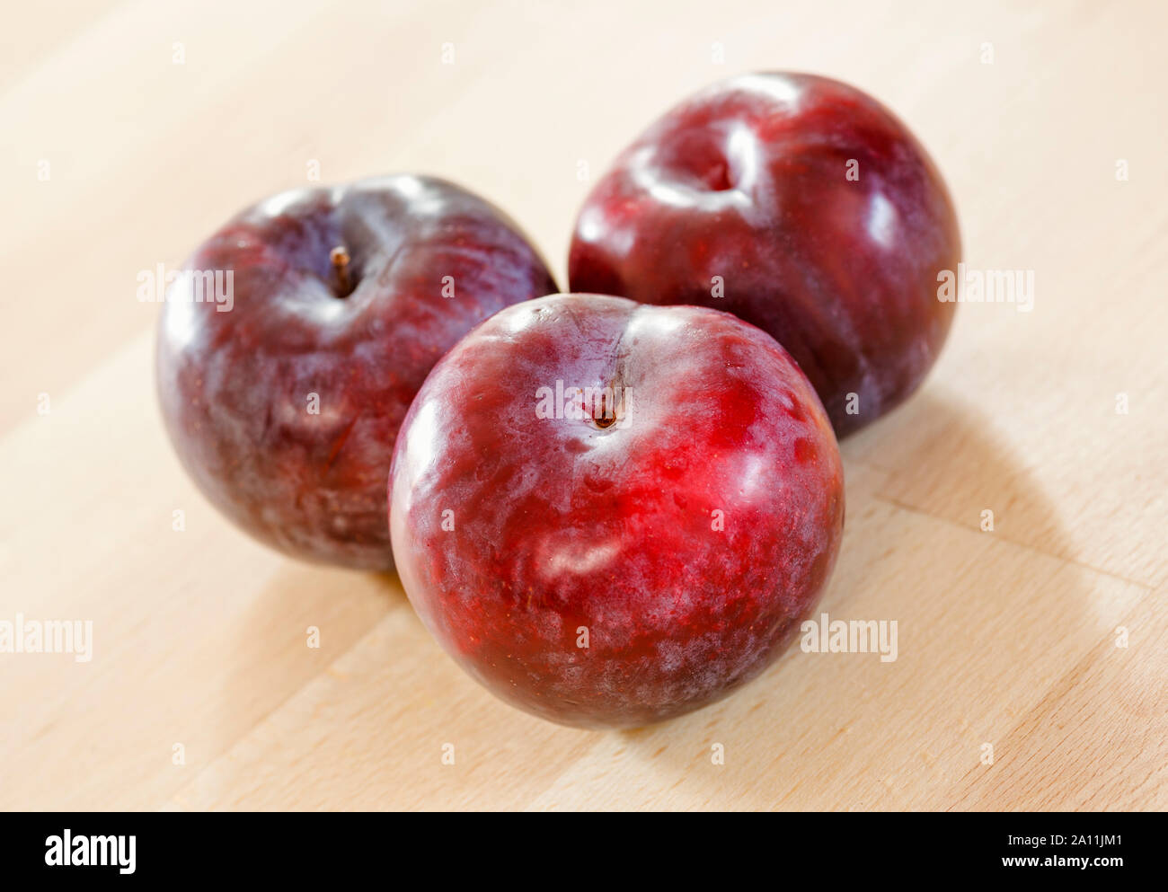Trois prunes on a wooden surface Banque D'Images