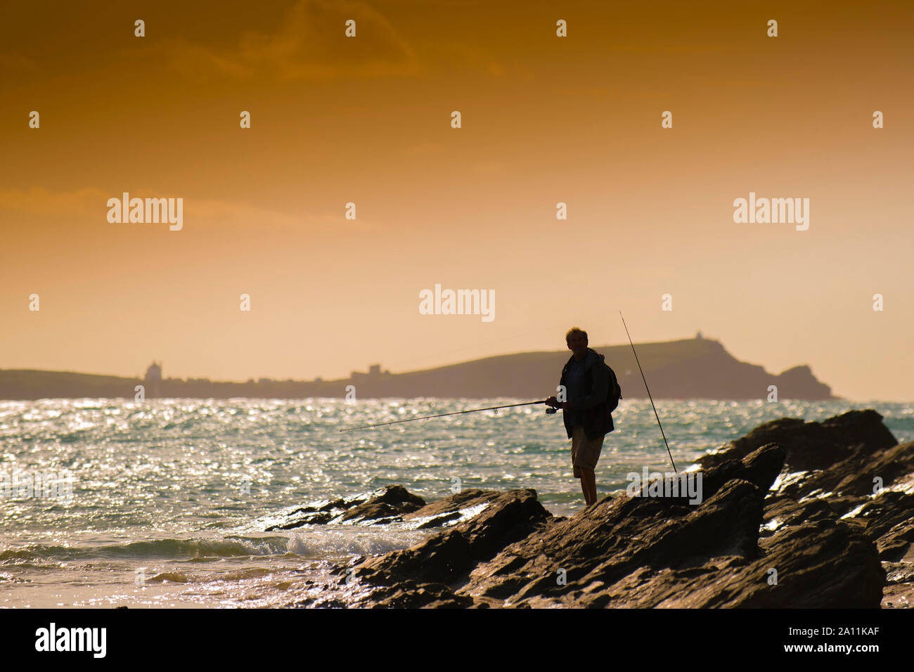 La silhouette d'un pêcheur à la pêche à pied sur la plage de Porth Newquay en Cornouailles. Banque D'Images