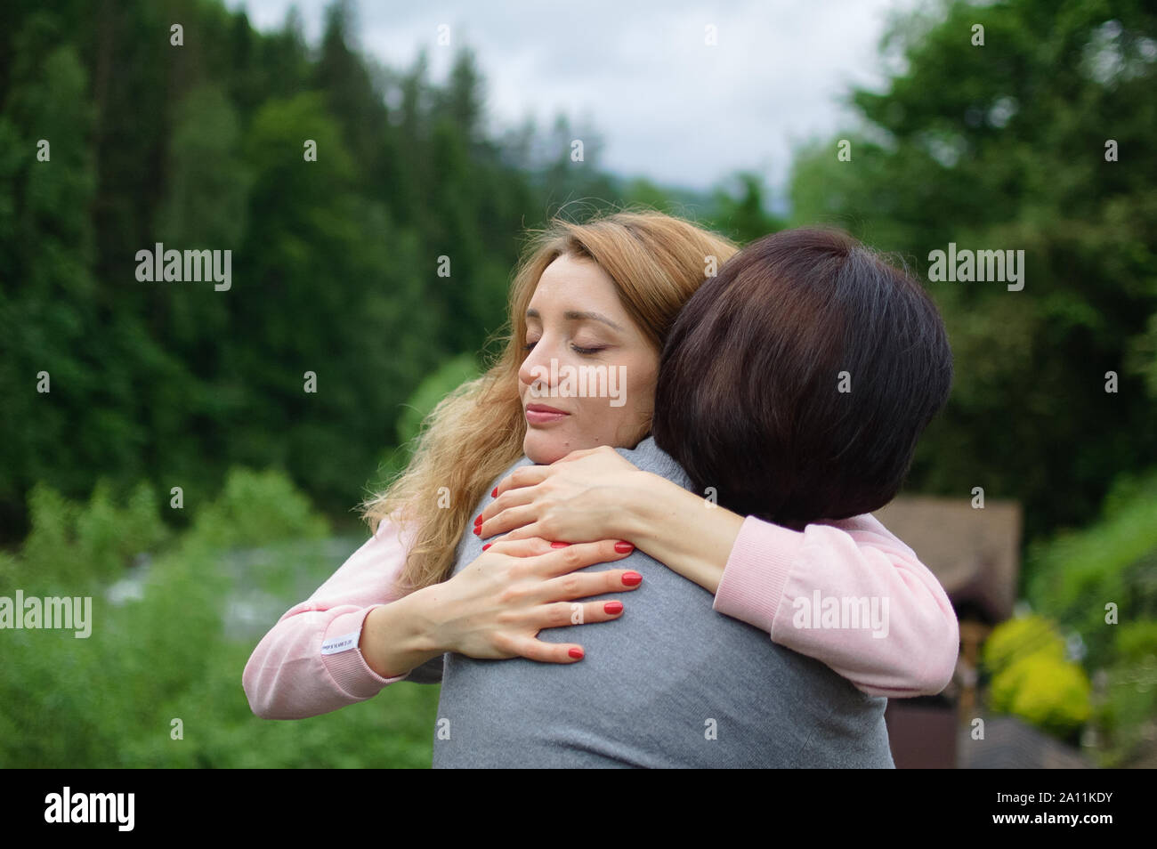 Jeune femme blonde est l'étreindre mère senior bénéficiant d'être ensemble dans les montagnes pendant les vacances. Concept de la tendresse, les soins, l'amour familial, re Banque D'Images