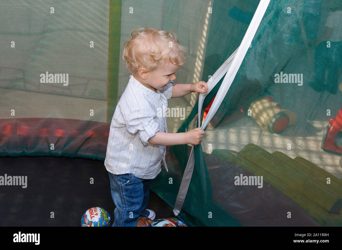 Portrait authentique et sincère d'un mignon sourire heureux de deux ans vieux cheveux blond petit garçon jouant à l'intérieur d'une fête d'enfant. Banque D'Images