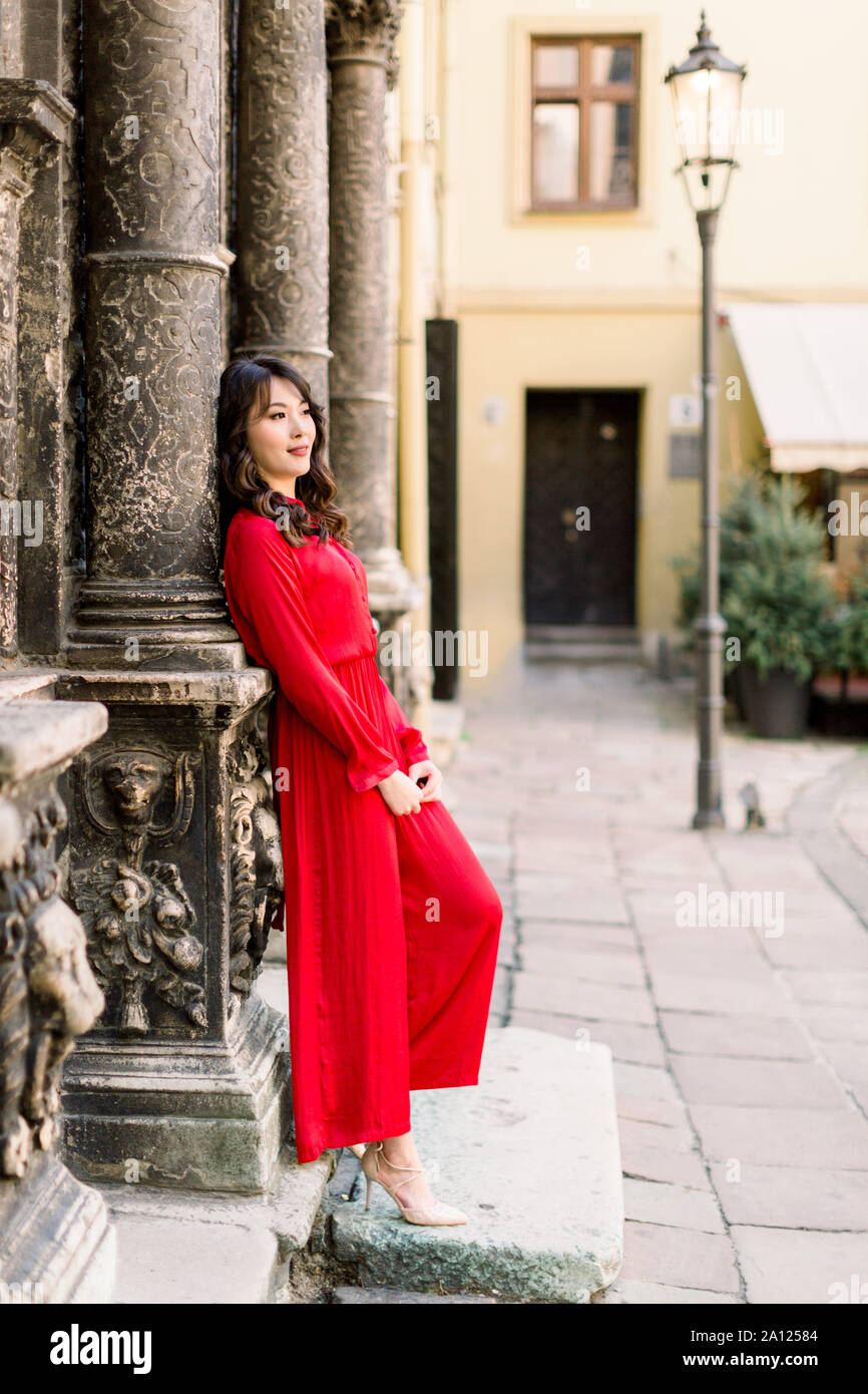 Jolie femme asiatique en robe rouge longue posant debout près de l'ancien  bâtiment colonne en vieille ville, l'histoire d'amour ou mariage de droit  en Europe Photo Stock - Alamy