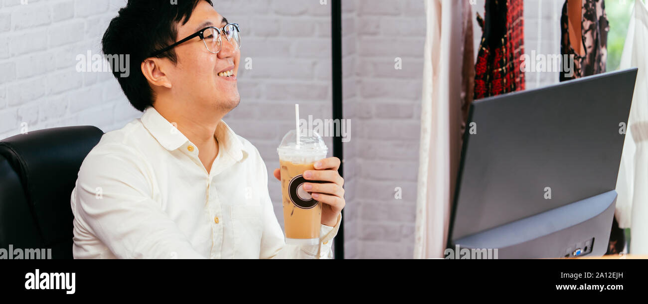 Vêtements professionnels bénéficiant d'entrepreneur et de boire du café au bureau. Young Asian man dans les verres à l'aide d'un ordinateur et d'obtenir livraison de commande de l'alimentation Banque D'Images