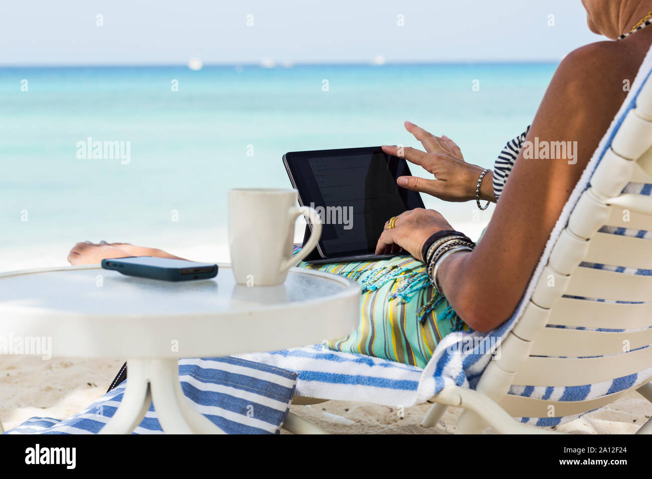 Femme adulte executive en utilisant un ordinateur portable sur la plage, l'île Grand Cayman Banque D'Images