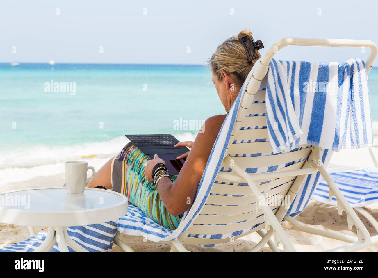 Femme adulte conseil d'utilisation de smart phone sur la plage, l'île Grand Cayman Banque D'Images