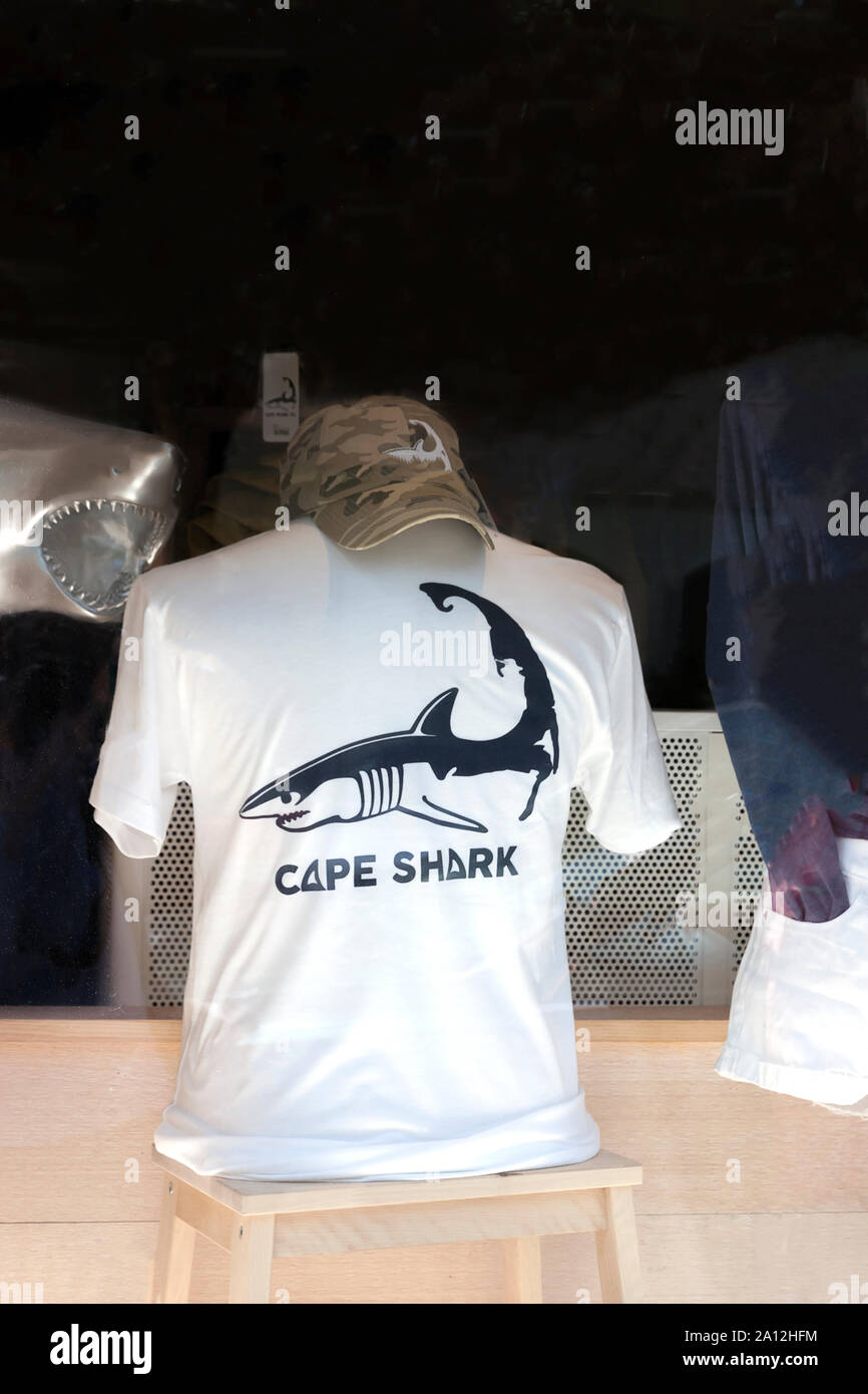 Tee-shirt sur le thème du requin et le cap à vendre dans la vitrine d'un magasin à Chatham, Cape Cod, Massachusetts, United States. Banque D'Images