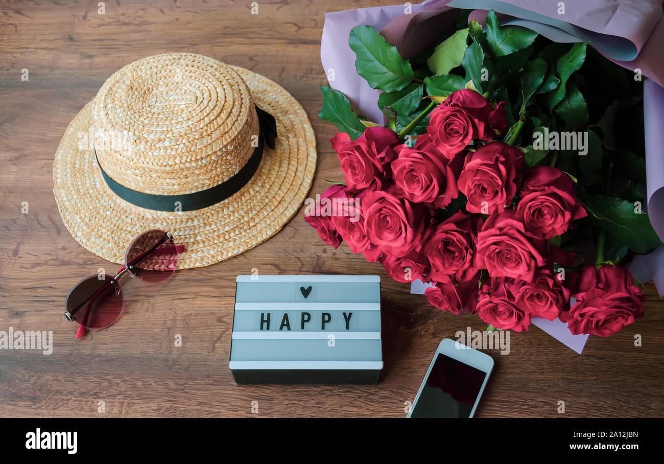 Inscription 'bonne journée' sur une table en bois avec un chapeau, un bouquet de roses et verres Banque D'Images