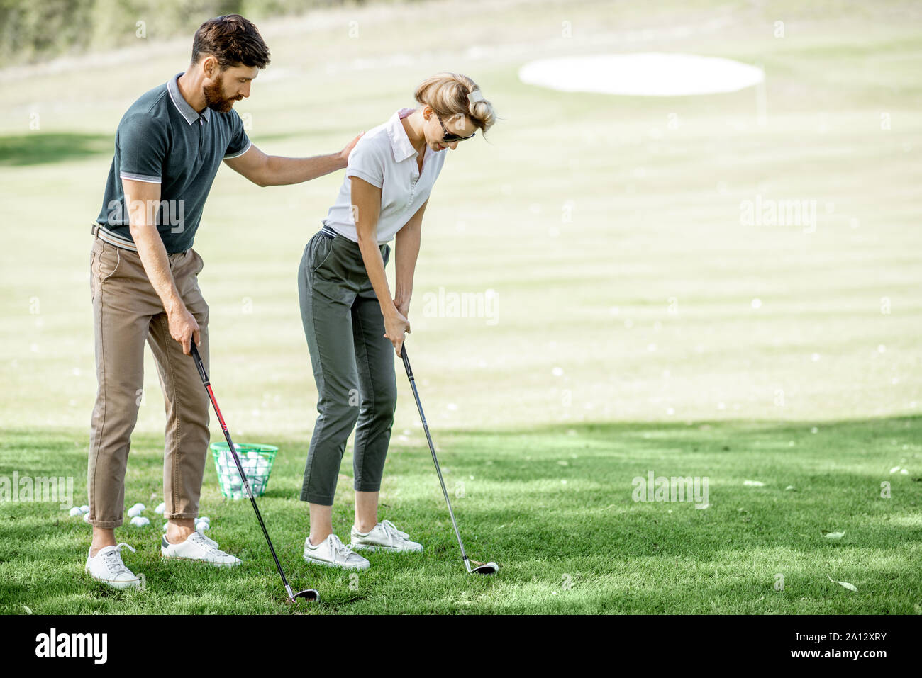 L'enseignement de l'instructeur mâle jeune femme pour jouer au golf sur le parcours de golf sur une journée ensoleillée Banque D'Images
