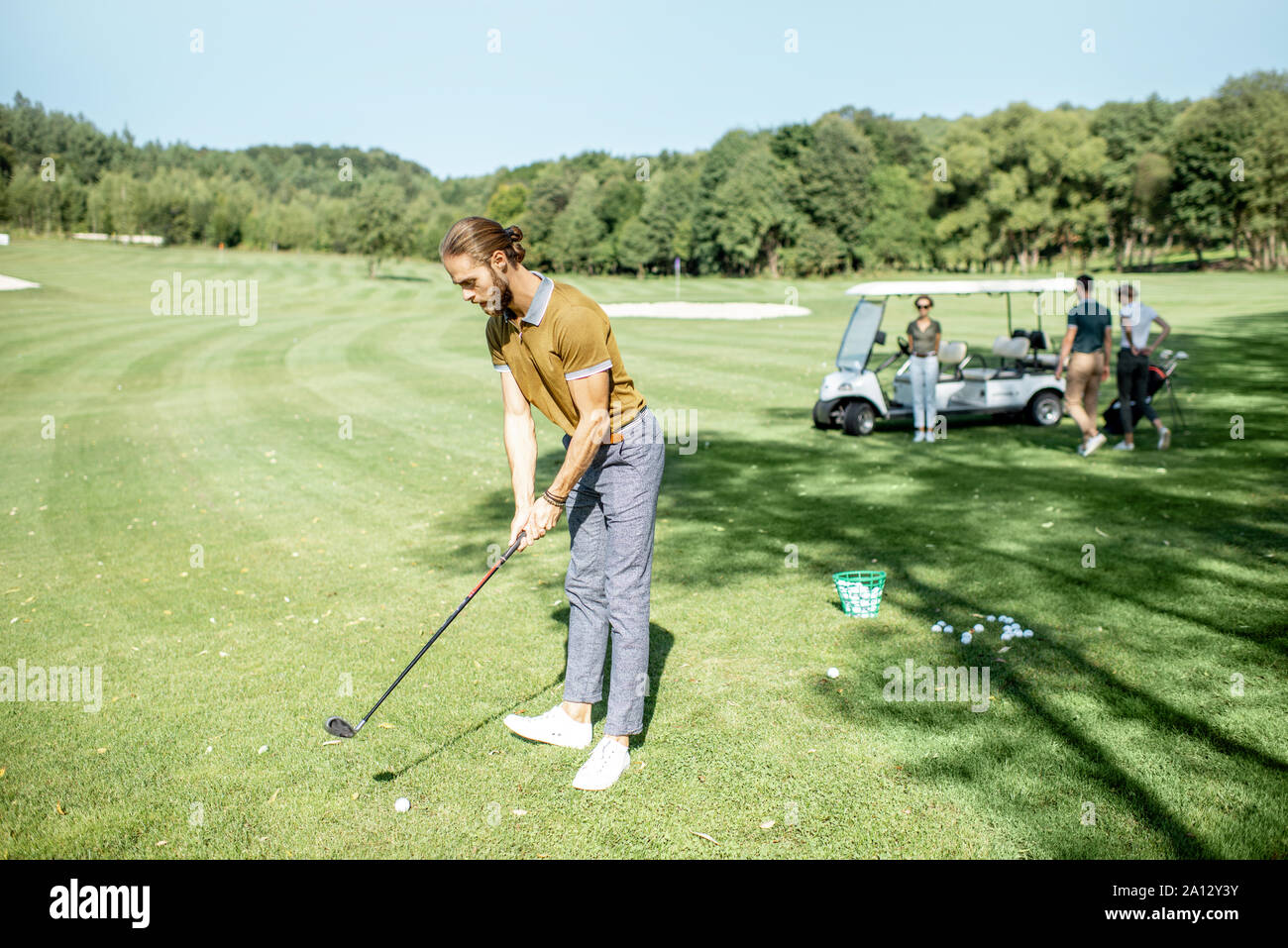 L'homme jouant le golf, se balancer avec le putter sur un beau parcours sur une journée ensoleillée Banque D'Images