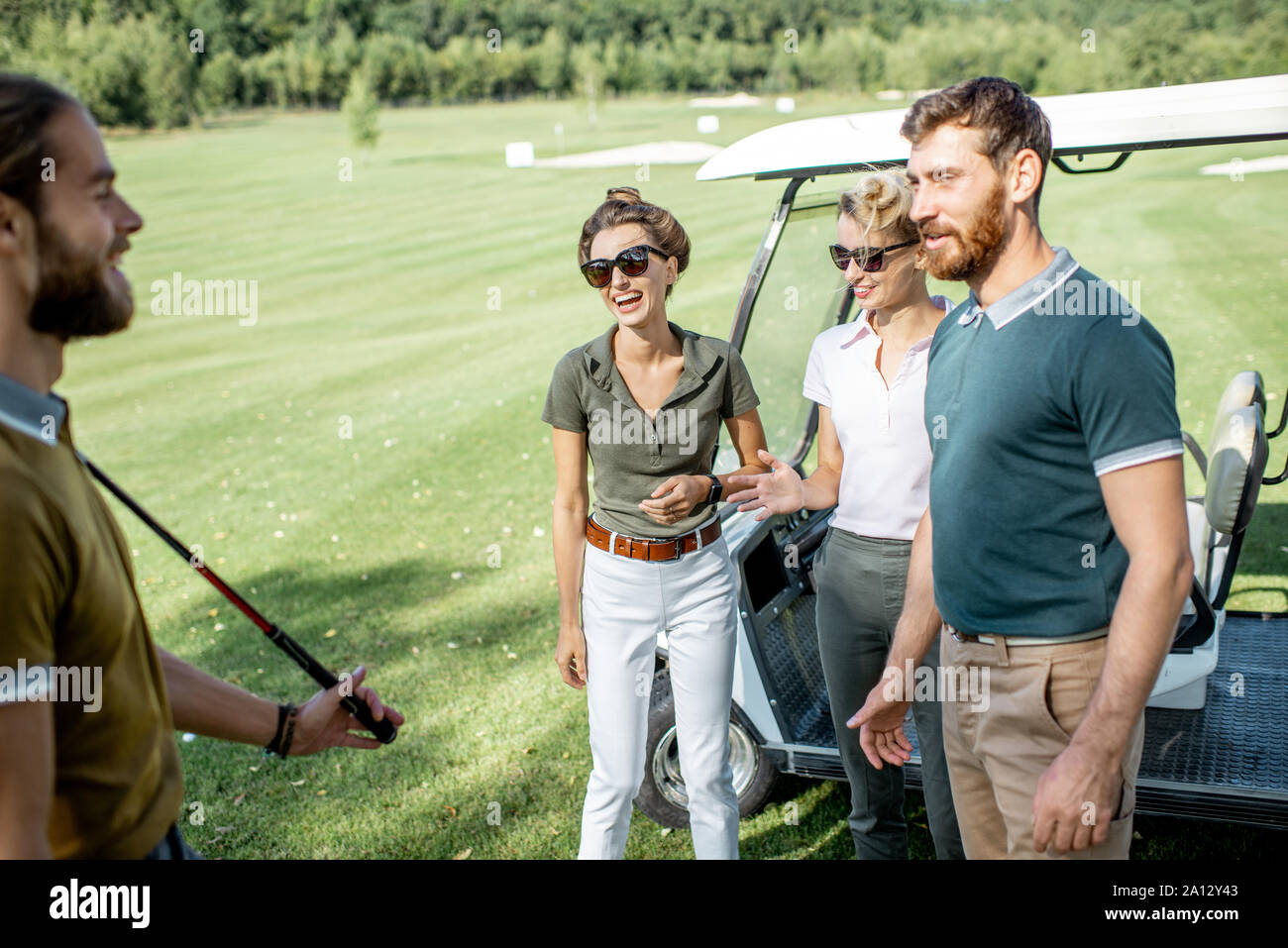 Un groupe de jeunes professionnels amis rassemblement devant le jeu de golf près de la voiture sur un parcours à jouer sur une journée ensoleillée Banque D'Images