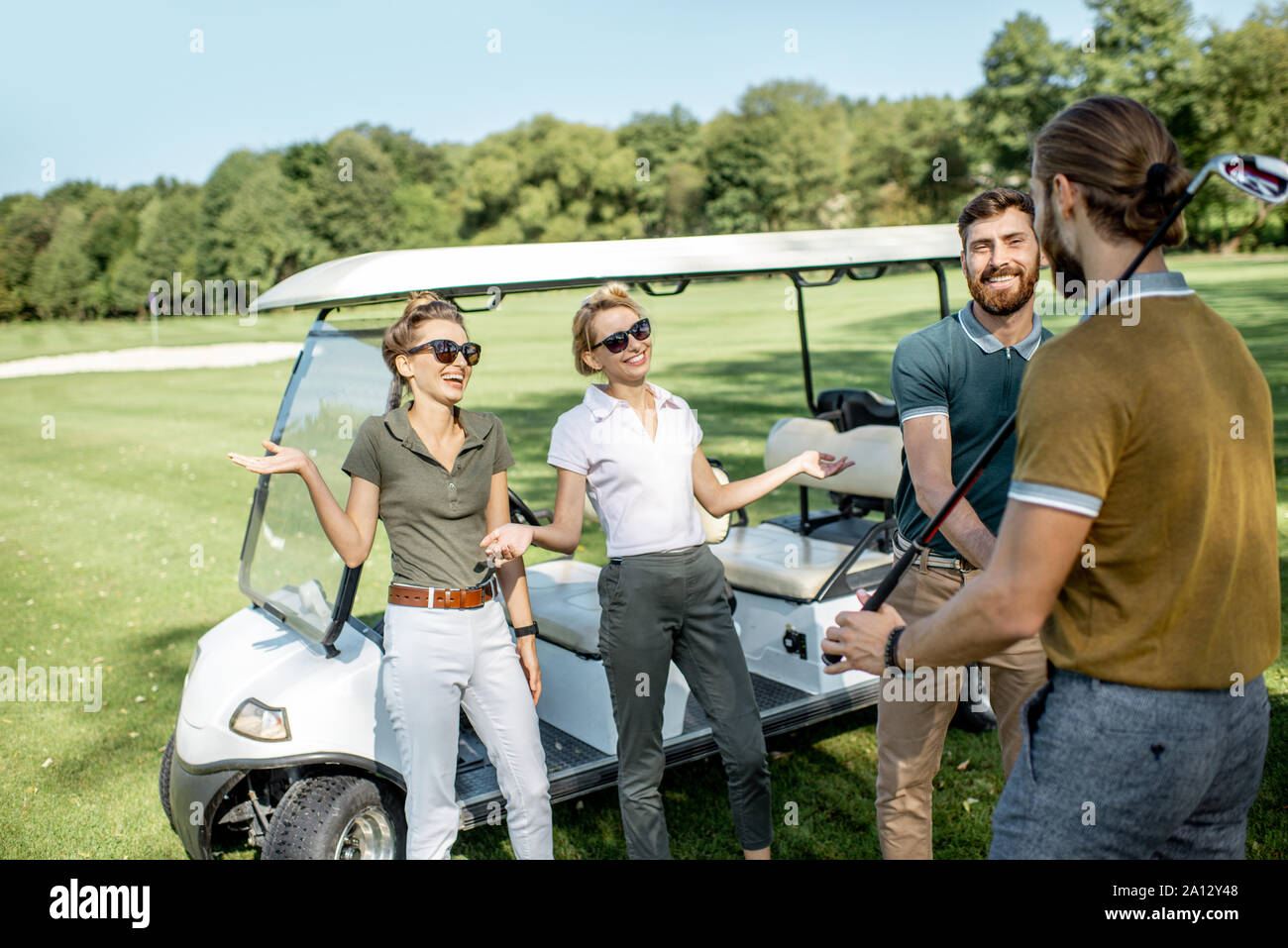 Un groupe de jeunes professionnels amis rassemblement devant le jeu de golf près de la voiture sur un parcours à jouer sur une journée ensoleillée Banque D'Images