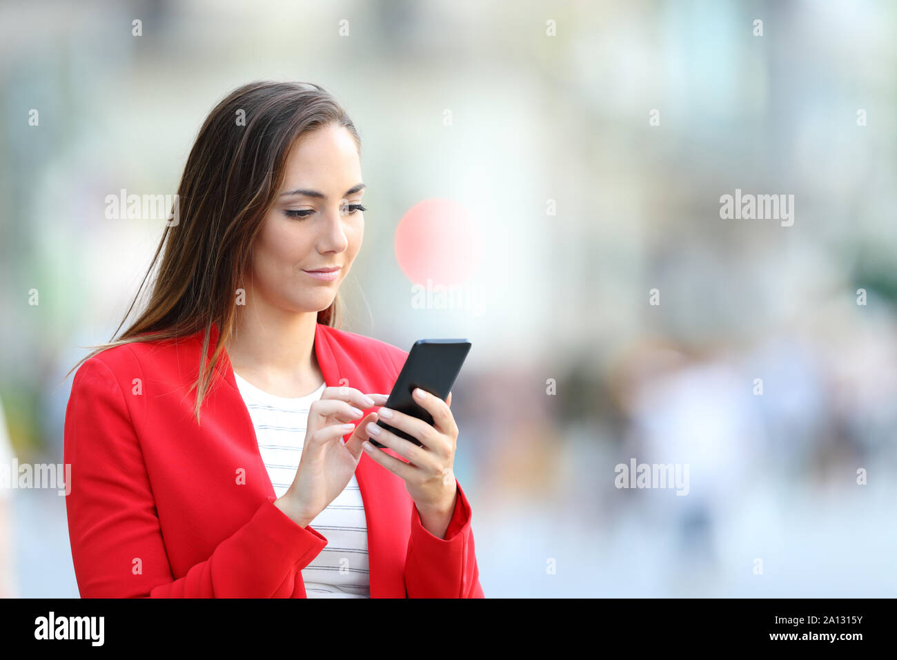 Femme élégante Graves en rouge à l'aide de smart phone debout dans la rue Banque D'Images