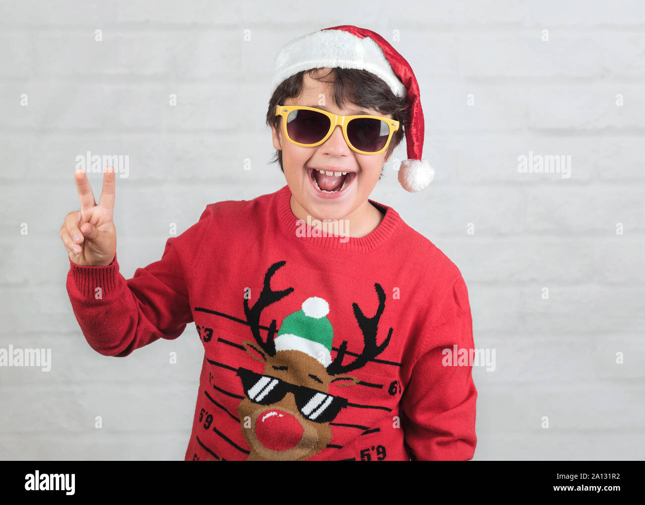 Smiling child Wearing Christmas Santa Claus Hat avec des lunettes de soleil sur fond brique Banque D'Images