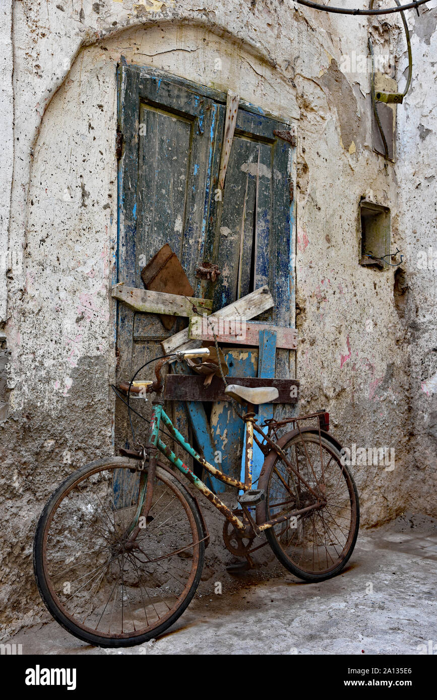 Vieux, rouillé location garé contre un Marocain délabrée porte à un mur blanchi à la chaux typique de l'expression même de la ville d'Essaouira, Maroc, Afrique. Banque D'Images