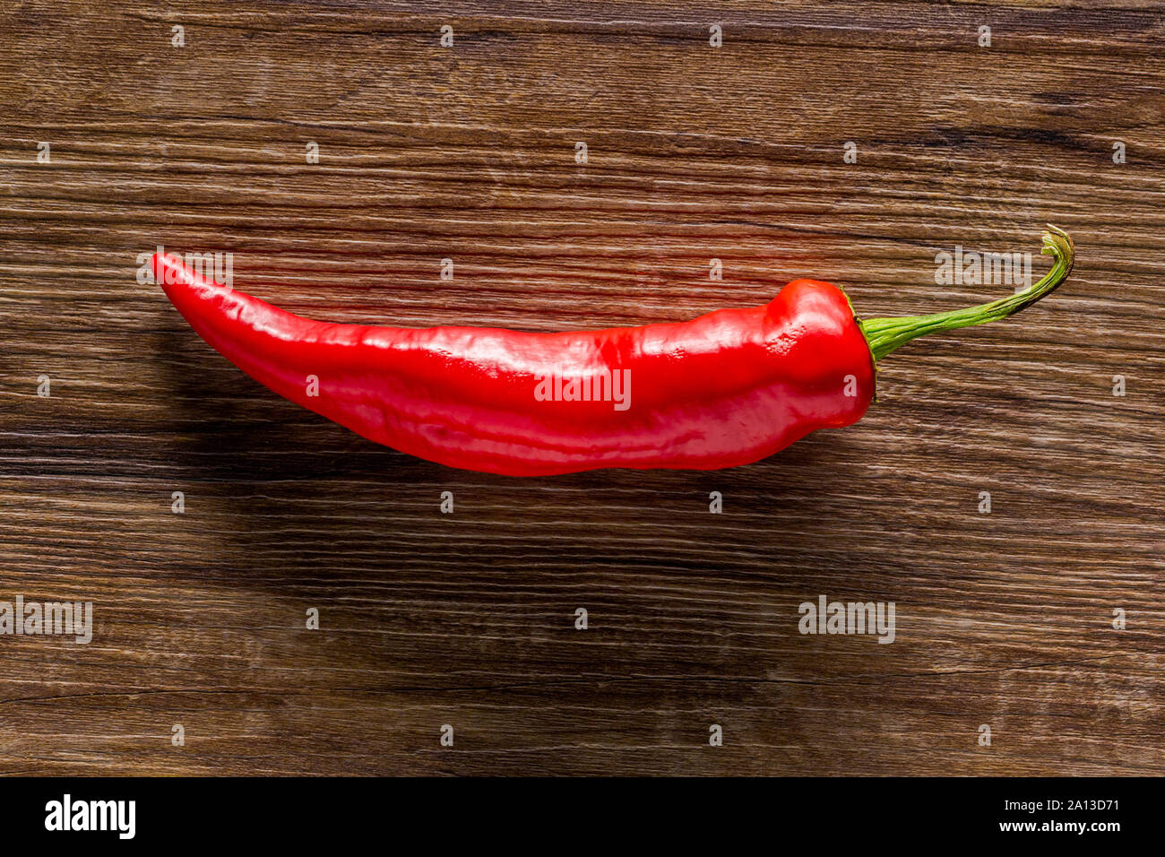 Une nouvelle banane rouge poivre sur un fond de bois foncé texturé Banque D'Images