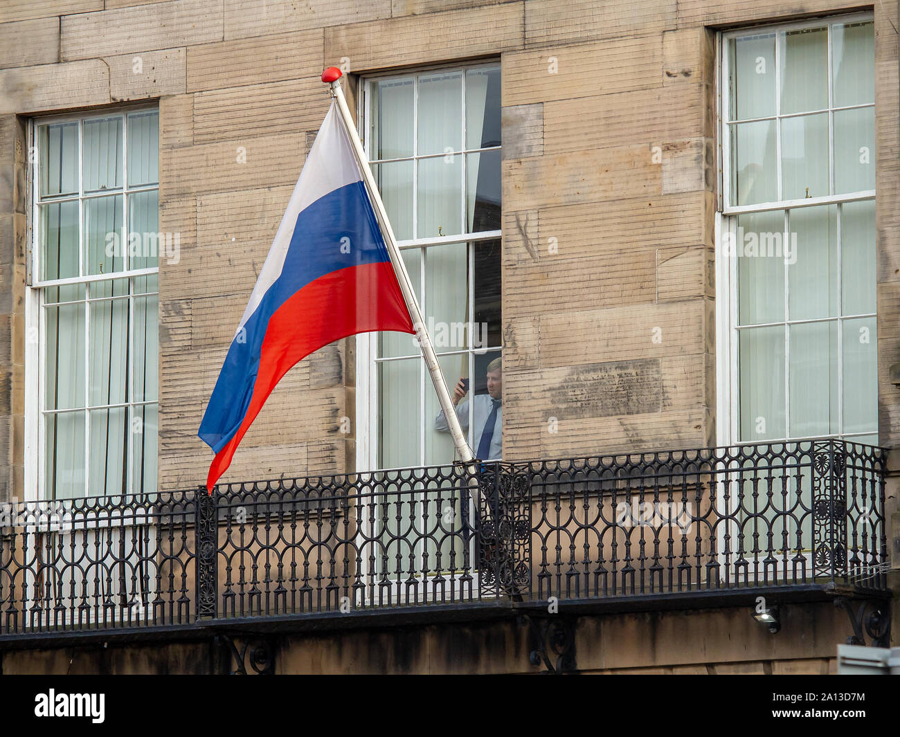 Un homme regarde l'action du consulat général de la Fédération de Russie, située sur la rue Melville. Fast & Furious 9 a terminé la production dans Édimbourg, après plusieurs semaines de tournage du dernier film dans les poursuite de voitures franchise. Les dernières scènes ont été tournées aujourd'hui sur rue Melville, une jolie terrasse géorgienne dans la capitale du West End. Stunt drivers, debout dans des stars telles que Vin Diesel, conduisent leurs voitures de muscle en haut et en bas de la rue, aux côtés des véhicules de l'appareil photo. Fast & Furious 9 est prévu pour le 22 mai 2020. Banque D'Images