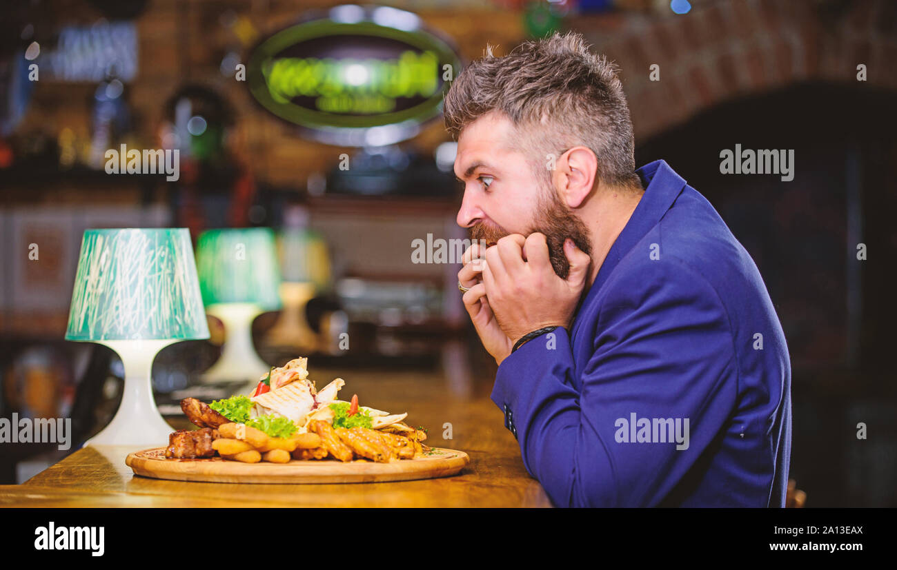 L'homme a reçu de pommes de terre frites repas avec les bâtonnets de poisson viande. Profitez de repas. Des calories. Tricher repas. Hipster faim manger pub aliments frits. Costume officiel Gestionnaire de siéger au comptoir du bar. Délicieux repas. Banque D'Images