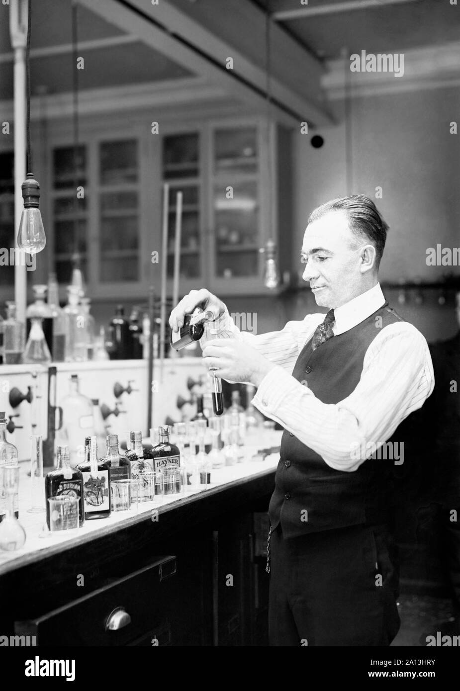 Chimiste G. F. Beyer test d'une bouteille d'alcool de contrebande pendant la prohibition. Banque D'Images