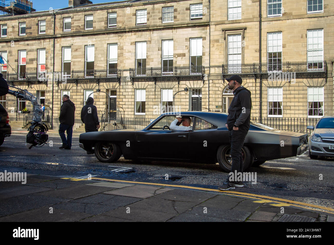 Vin Diesel's stand-in à propos de filmer une scène. Fast & Furious 9 a terminé la production dans Édimbourg, après plusieurs semaines de tournage du dernier film dans les poursuite de voitures franchise. Les dernières scènes ont été tournées aujourd'hui sur rue Melville, une jolie terrasse géorgienne dans la capitale du West End. Stunt drivers, debout dans des stars telles que Vin Diesel, conduisent leurs voitures de muscle en haut et en bas de la rue, aux côtés des véhicules de l'appareil photo. Fast & Furious 9 est prévu pour le 22 mai 2020. Banque D'Images