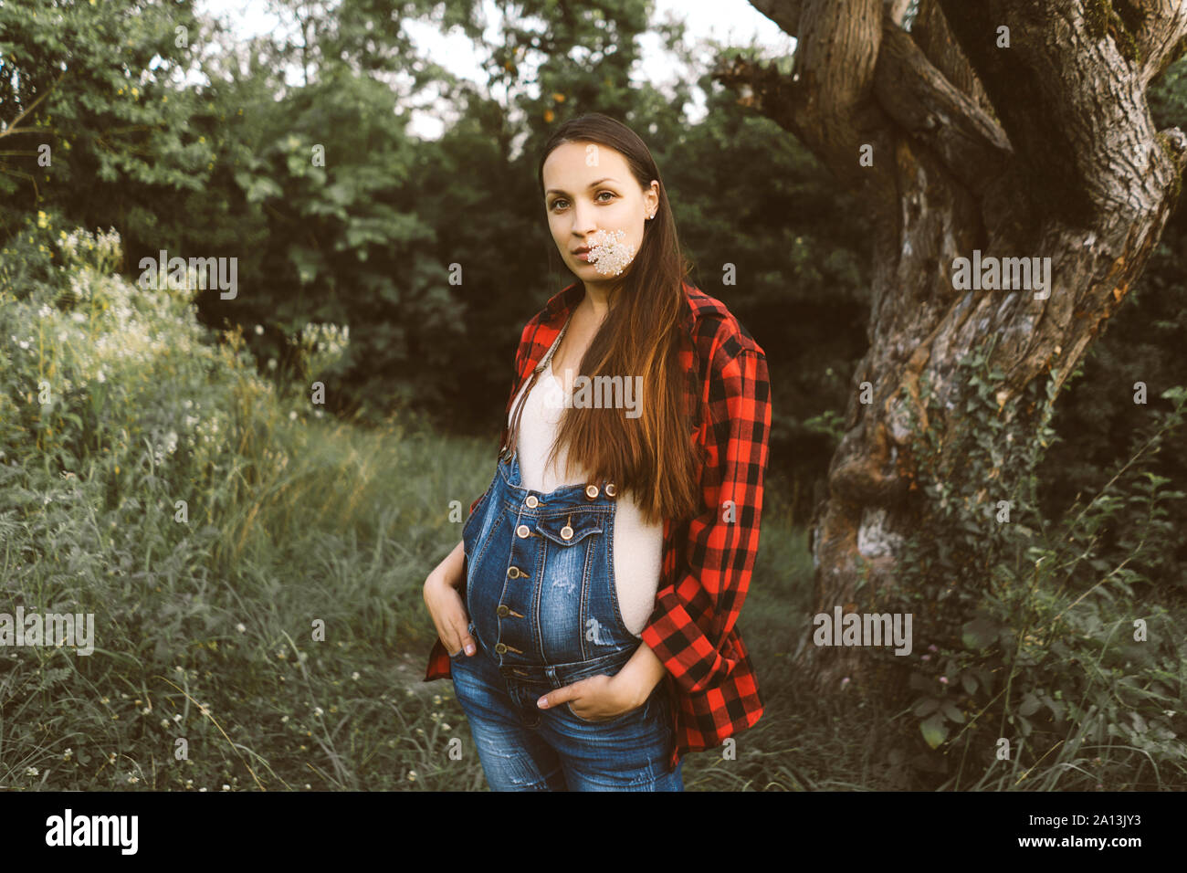 Femme enceinte en salopette en jean sur un arriere plan de la nature Photo Stock Alamy