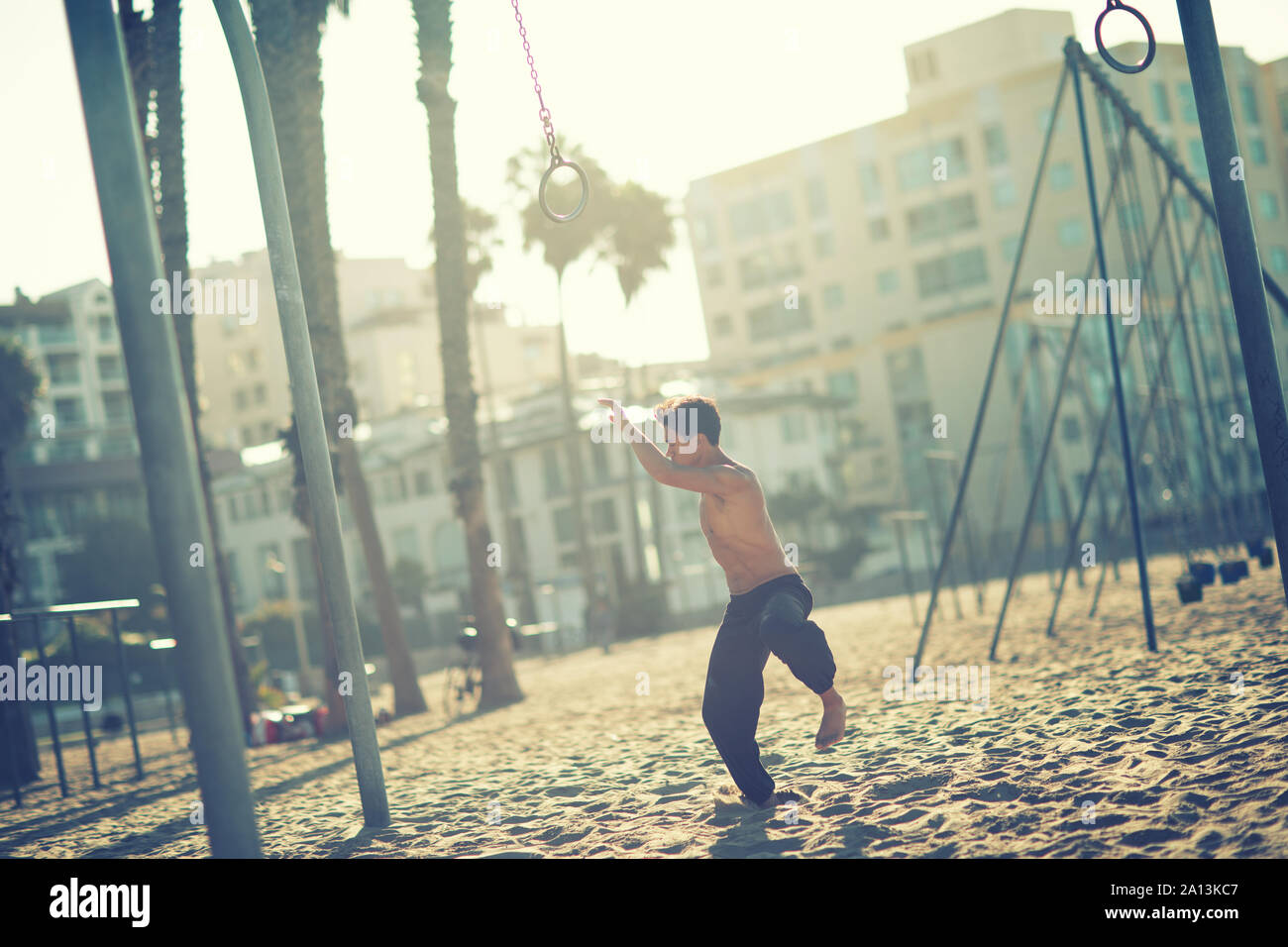 Un jeune homme sportif travaillant sur des anneaux de voyage sur Muscle Beach, Santa Monica, Californie Banque D'Images