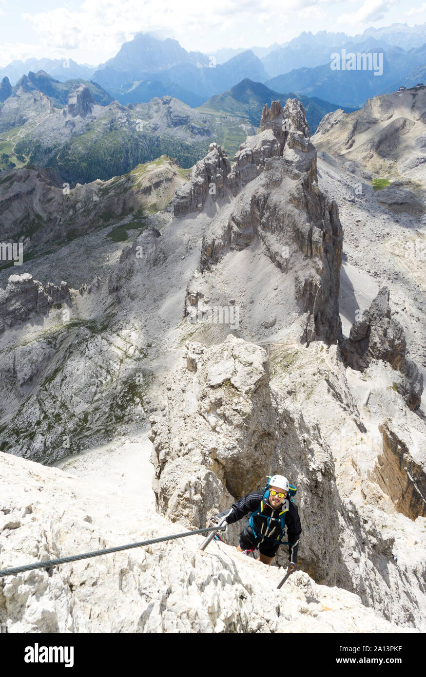 Beau mâle jeune grimpeur sur une pente raide et rocheuse exposée grimpe une Via Ferrata en Alta Badia dans le Tyrol du Sud Banque D'Images