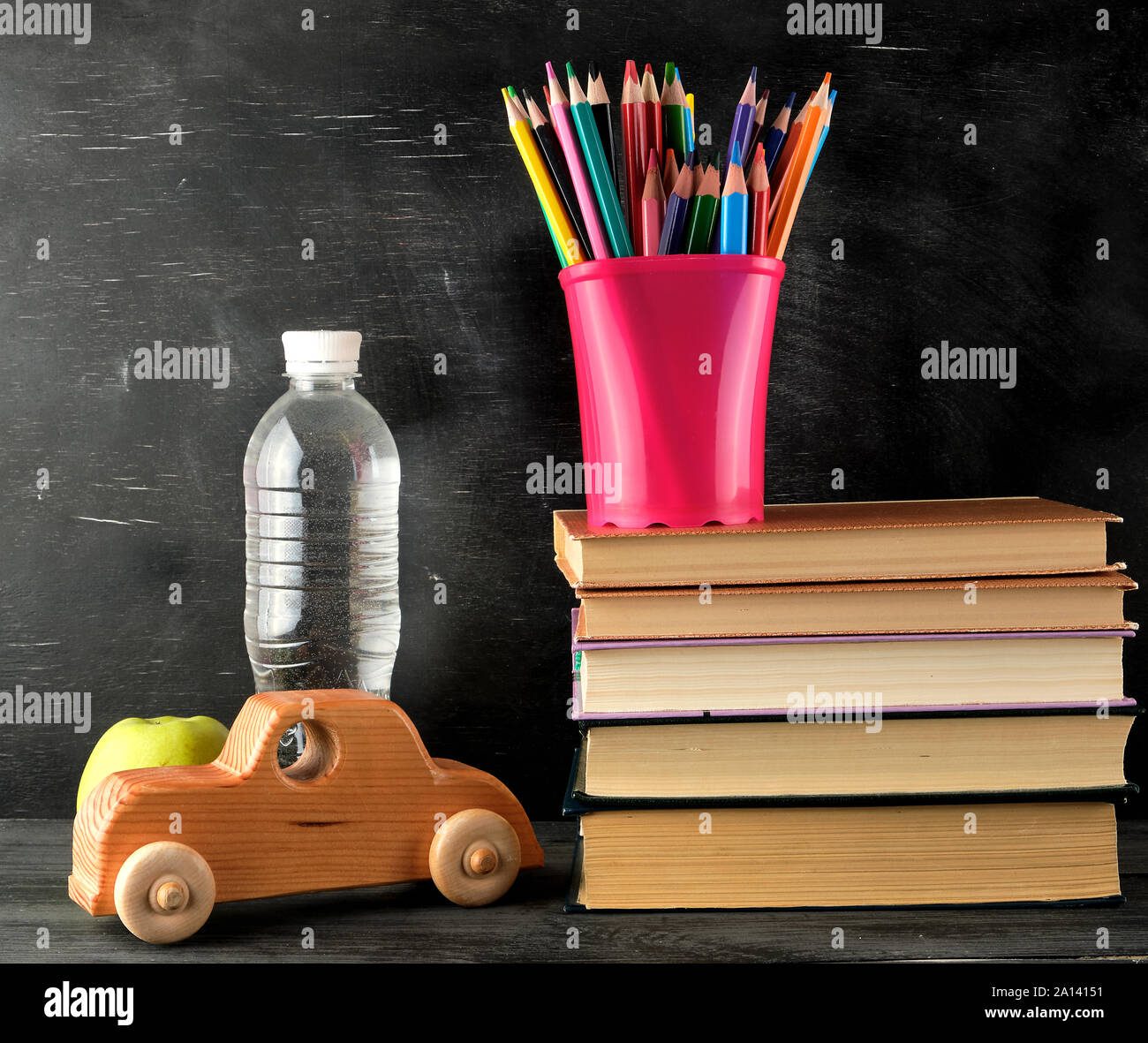 Pile de livres et d'une papeterie rose verre avec des crayons en bois multi-couleur, voiture, concept retour à l'école Banque D'Images