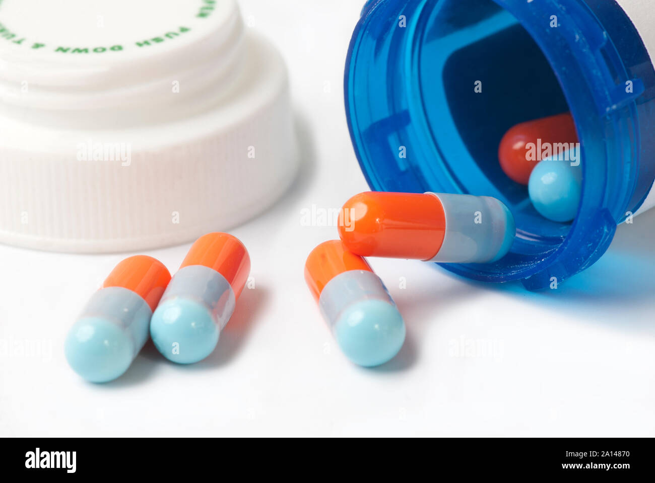 Capsules bleu et orange bleu avec flacon de médicaments sur blanc. Banque D'Images