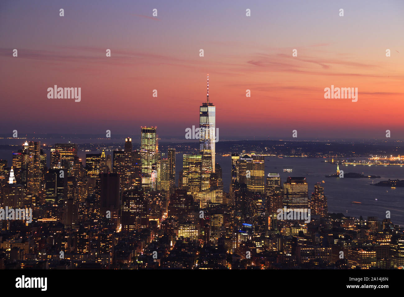 Vue aérienne de la ville de New York, Manhattan skyline allumé au coucher du soleil dont un World Trade Center et Liberty Island, États-Unis Banque D'Images