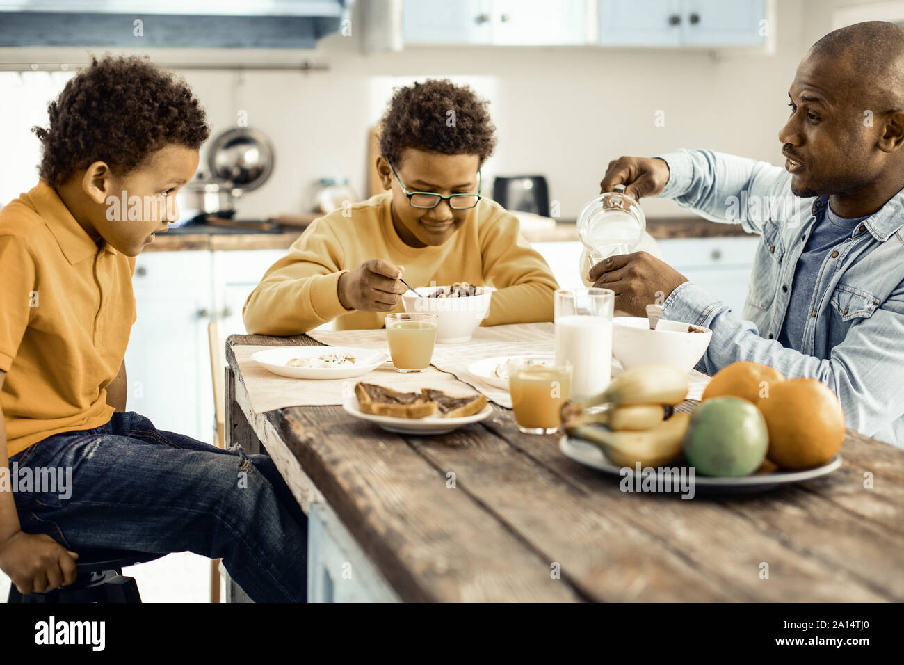 Papa préparer le petit-déjeuner pour son fils et enfin de s'asseoir pour manger avec eux. Banque D'Images